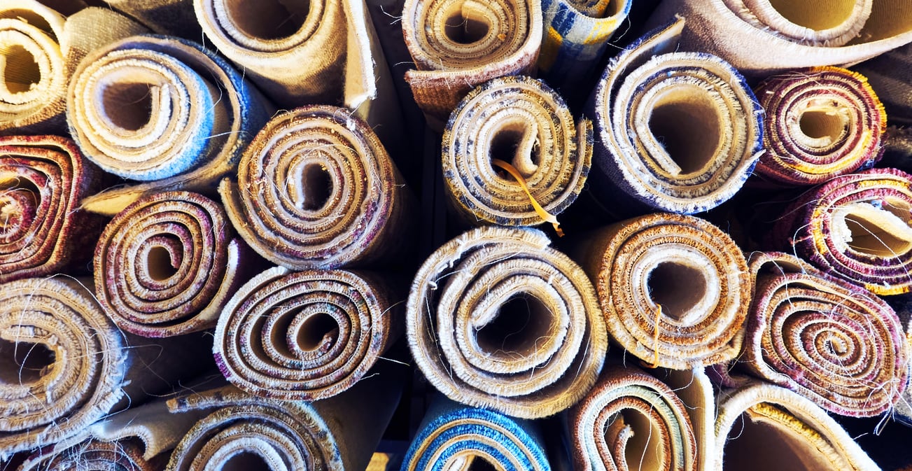 Variety of colorful carpets rolled up for display in a carpet store